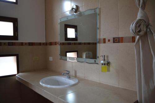ein Bad mit einem Waschbecken und einem Spiegel in der Unterkunft Hotel PrincesaToa in Quilotoa