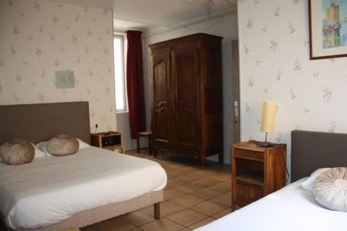 a bedroom with two beds and a wooden cabinet at Hôtel République in Dijon
