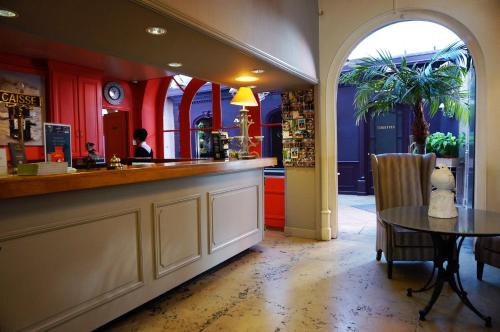 a restaurant with a bar with a table and a person in the background at LOGIS Hôtel de Bourgogne - Mâcon in Mâcon