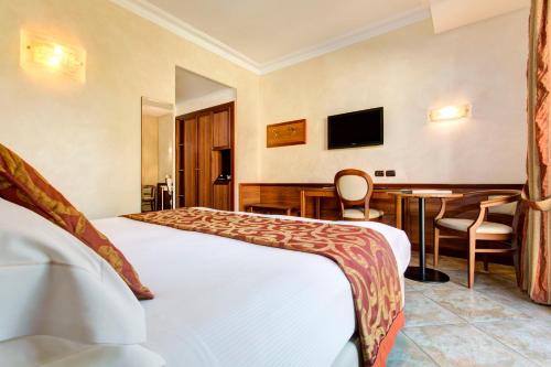 a hotel room with two beds and a desk at Hotel Athena in Siena