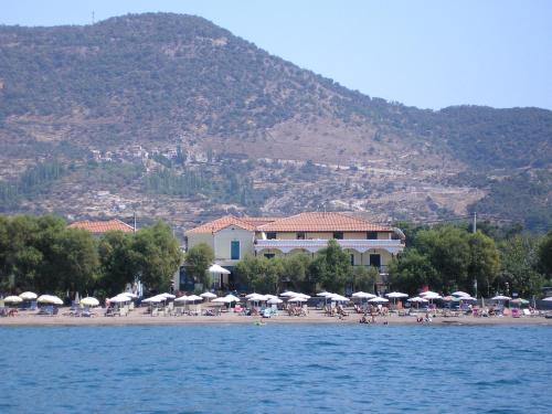 a beach with umbrellas and people sitting on the beach at Hotel Ilion in Petra