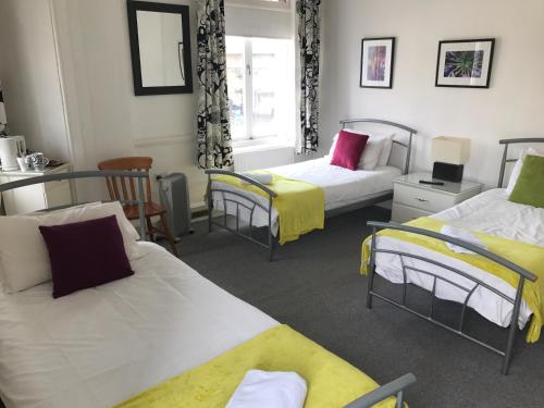 倫敦的住宿－安格斯坦酒店，一间设有三张黄色和白色床铺的房间