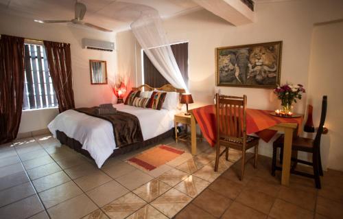 a bedroom with a bed and a table and a desk at Manzini Cottage in Marloth Park