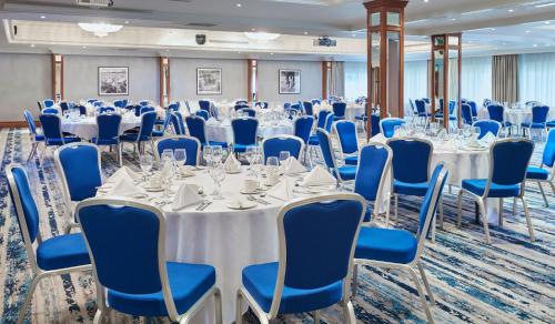 a conference room with white tables and blue chairs at Leonardo Hotel Cheltenham in Cheltenham