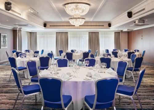 a conference room with tables and chairs and a chandelier at Leonardo Hotel Cheltenham in Cheltenham