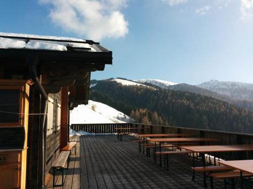 a deck with tables and benches on a ski slope at Casetta next to the Creek Dino Buzzati in Belluno
