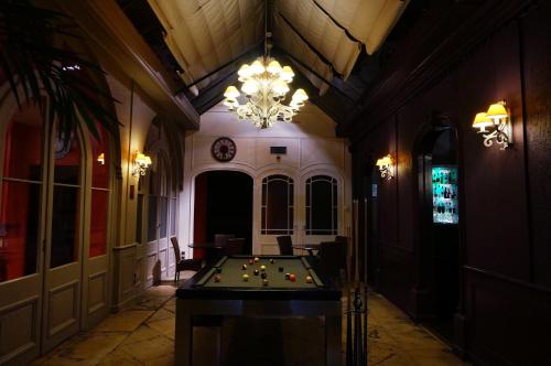 a room with a pool table and a chandelier at LOGIS Hôtel de Bourgogne - Mâcon in Mâcon