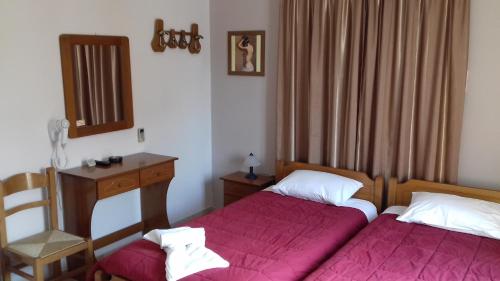 a bedroom with two beds and a desk and a mirror at Kabanis Rooms in Ermoupoli