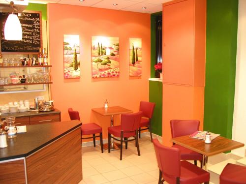 un restaurante con sillas rojas, mesas y pinturas en la pared en Wohnen beim Bäcker Weinberger, en Ybbs an der Donau