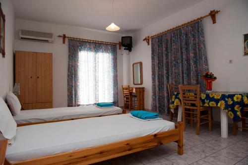 a bedroom with two beds and a table and chairs at Syraina Apartments in Skiathos Town