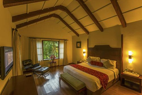 - une chambre avec un grand lit et une télévision dans l'établissement The Windflower Resort & Spa, Coorg, à Suntikoppa