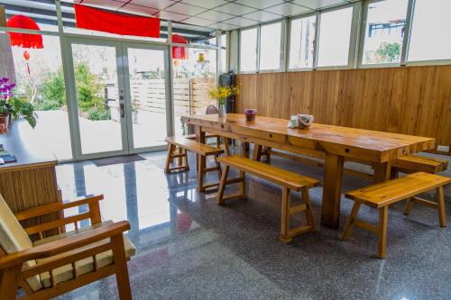 a wooden table and benches in a room with windows at Just Stay 稼軒 in Yuanshan
