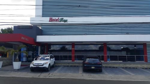 two cars parked in a parking lot in front of a building at Hotel Rey in Concepción de La Vega
