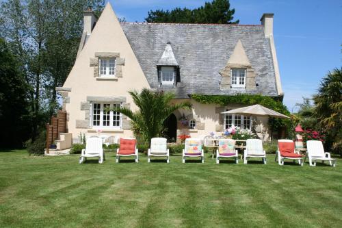 a group of chairs sitting on a lawn in front of a house at Chez Renée et Raynal B&B in Plounévez-Lochrist