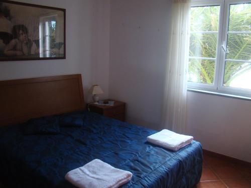 a bedroom with a bed with two towels on it at Casa das Merces in Angra do Heroísmo
