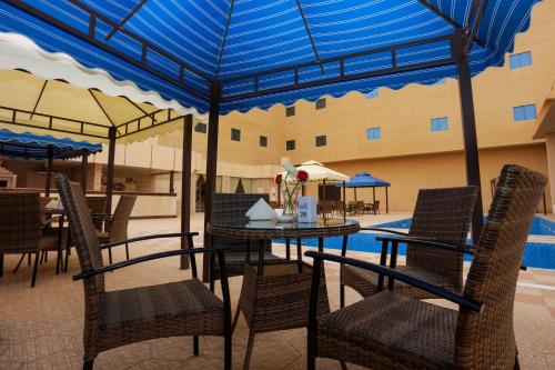 un patio con tavolo, sedie e piscina di Hala Inn Arar Hotel a Arar