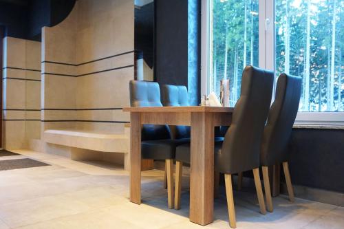 a dining room table with black chairs and a window at Villa Winterpol in Karpacz
