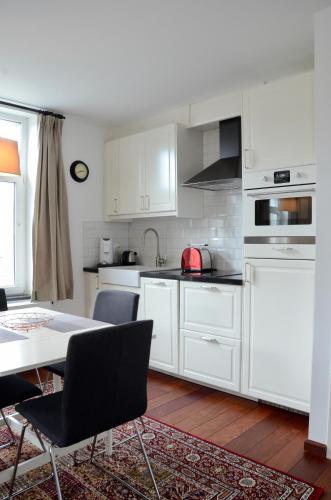 a kitchen with white cabinets and a table with chairs at Le Baron Apartments in Stavelot