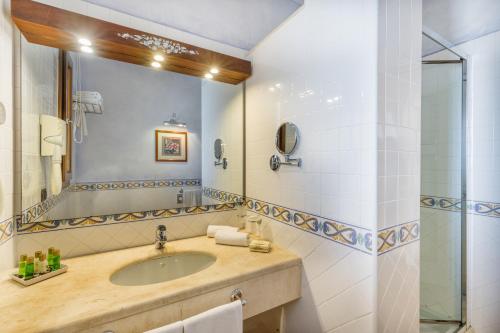a bathroom with a sink, mirror, and bathtub at La Vecchia Fonte Boutique Hotel in Palau