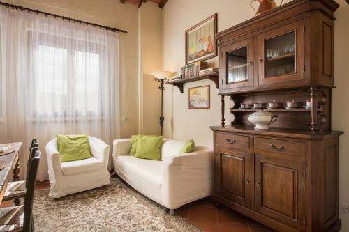 a living room with two white chairs and a cabinet at Casa Vacanze Villa il Castellaccio in Lucolena in Chianti