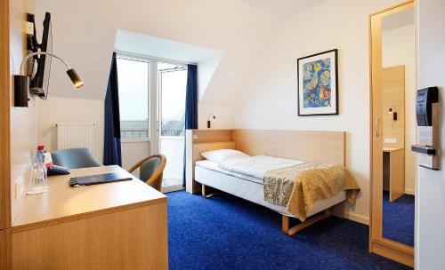 a bedroom with a bed and a desk and a window at Herning City Hotel in Herning
