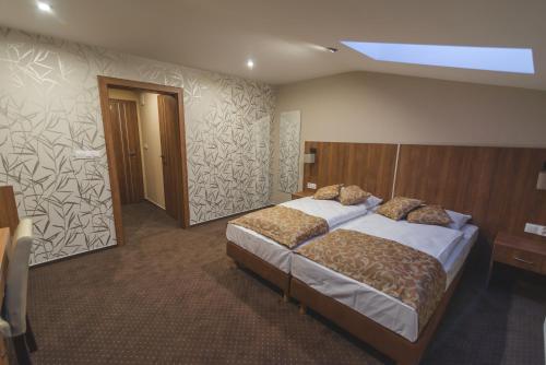 ein Schlafzimmer mit einem Bett und einer Holzwand in der Unterkunft Grillbar Penzion & Restaurant in Spišská Nová Ves