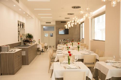 une salle à manger avec des tables et des chaises blanches dans l'établissement Hotel Ristorante Rinelli, à Margherita di Savoia