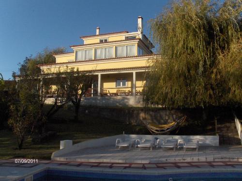 a large yellow house with chairs in front of it at AQC - A Quinta Chama in Caldas da Rainha