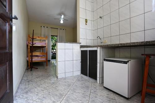 a kitchen with white tile walls and a refrigerator at Arco Íris Pousada in Ilha Comprida