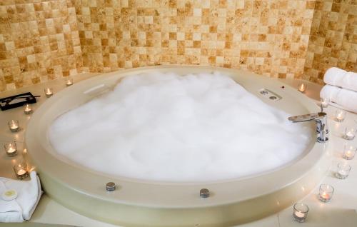 a bathroom with a bath tub with candles in it at El Golf Hotel Boutique in Lima