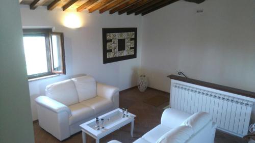a living room with white furniture and a window at Podere Le Volte degli Angeli in Spello
