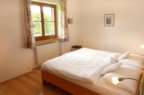 a bedroom with a white bed with a window at App Unterhoezlhof in Valdaora