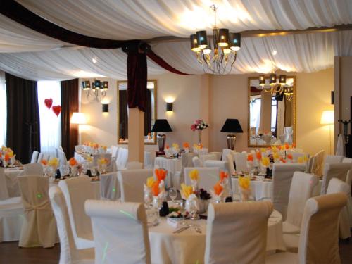 a room full of tables and chairs with white tables and chairs at Hotel Doro City in Tirana