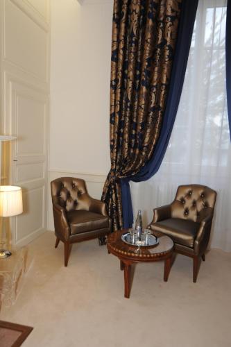two chairs and a coffee table in front of a window at Hôtel Victor Hugo in Pontorson