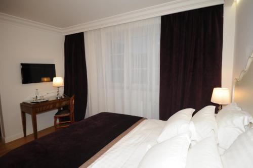 a bedroom with a bed with a desk and a window at Hôtel Victor Hugo in Pontorson