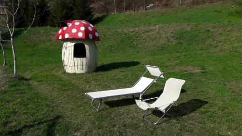 two chairs and a mushroom house in a field at Chalet Il Fungo in Averara