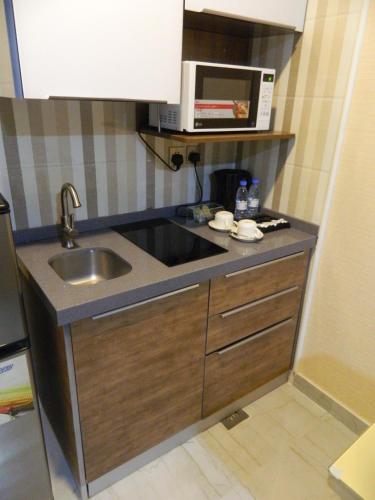 a small kitchen with a sink and a microwave at شركة منازل التوت للشقق المخدومة جده in Jeddah