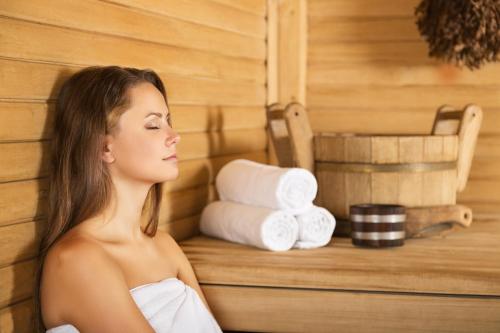 a woman sitting in a sauna with towels at Familotel Strandkind in Pelzerhaken