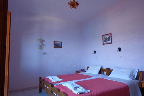 a bedroom with two beds with red and white sheets at Pension Galini in Armenistis