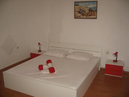 a white bed with two red bottles on it at Nevera Apartments Pašman,Banj in Banj