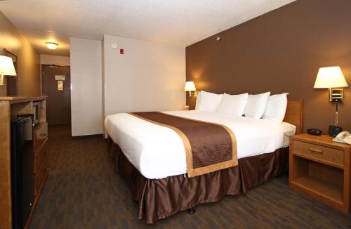 una habitación de hotel con una cama grande con sábanas blancas en New Victorian Inn & Suites Lincoln en Lincoln