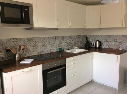 a kitchen with white cabinets and a sink at Maison de charme " Les Cyclamens" in Saint-Jorioz