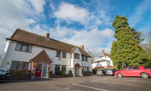 a white building with cars parked in a parking lot at Red Mullions Guest House in Oxford