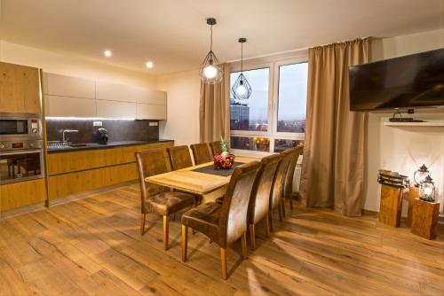 une cuisine et une salle à manger avec une table et des chaises en bois dans l'établissement A-PARTMAN SK - Main Square - Private Parking - Mountain View - Top Floor - 82 m2, à Poprad