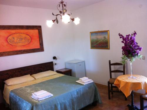 Un dormitorio con una cama y una mesa con un jarrón de flores en Agave Alghero, en Fertilia