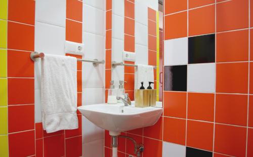 リスボンにあるSpin Hostelのオレンジと白のタイルを使用したバスルーム(シンク付)