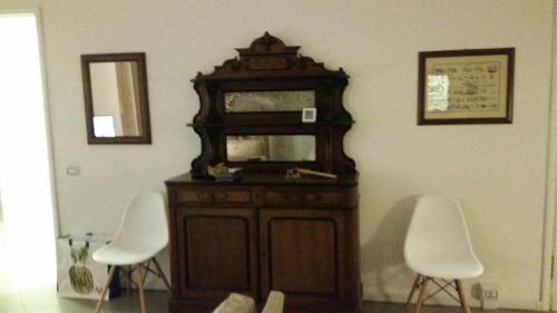 a wooden cabinet with two white chairs in a room at B&B Piazza Dante Nuoro in Nuoro