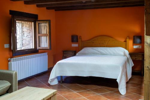 a bedroom with a bed with an orange wall at Molino del Medio in Robledillo de Gata