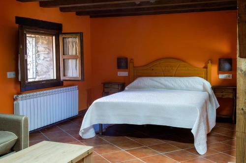 1 dormitorio con 1 cama con pared de color naranja en Molino del Medio, en Robledillo de Gata