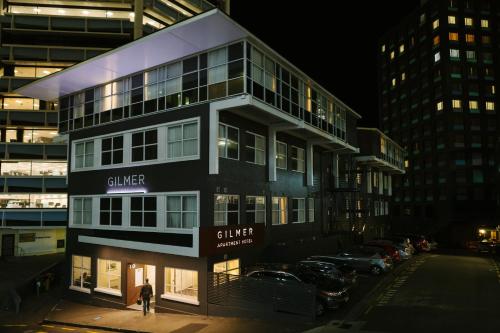 a man standing in front of a building at night at Gilmer Apartment Hotel in Wellington